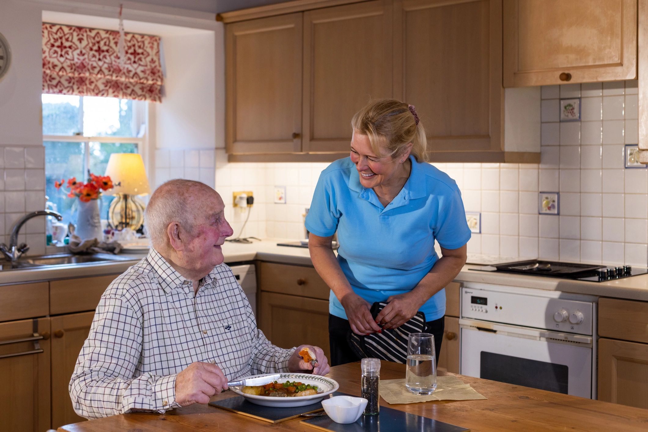 Caregiver serving a meal to a senior man at home