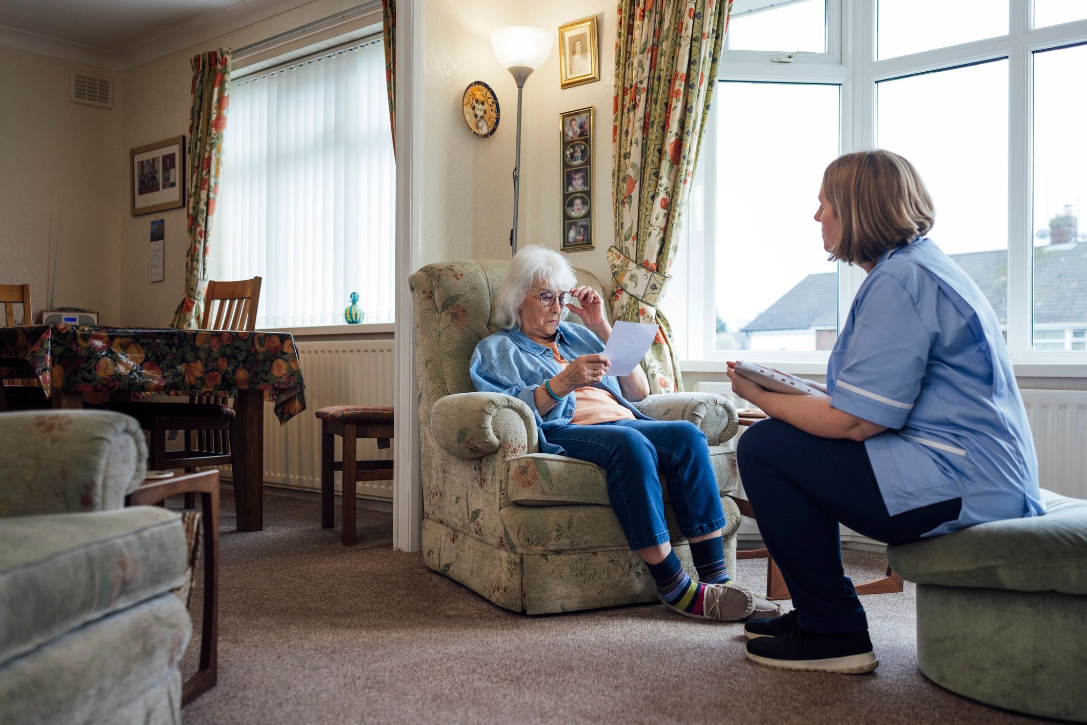 Home care professional speaking with an elderly woman in her living room
