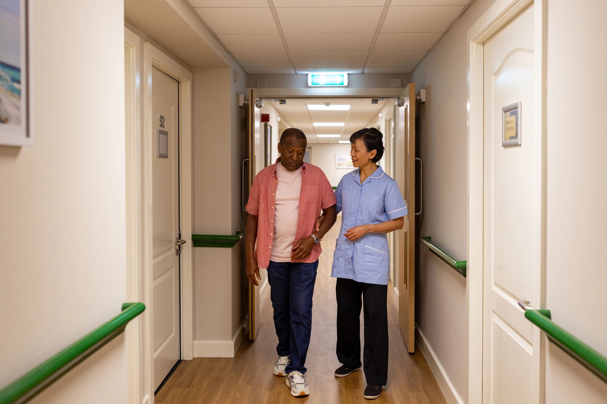 Care worker walking alongside an elderly resident while offering support