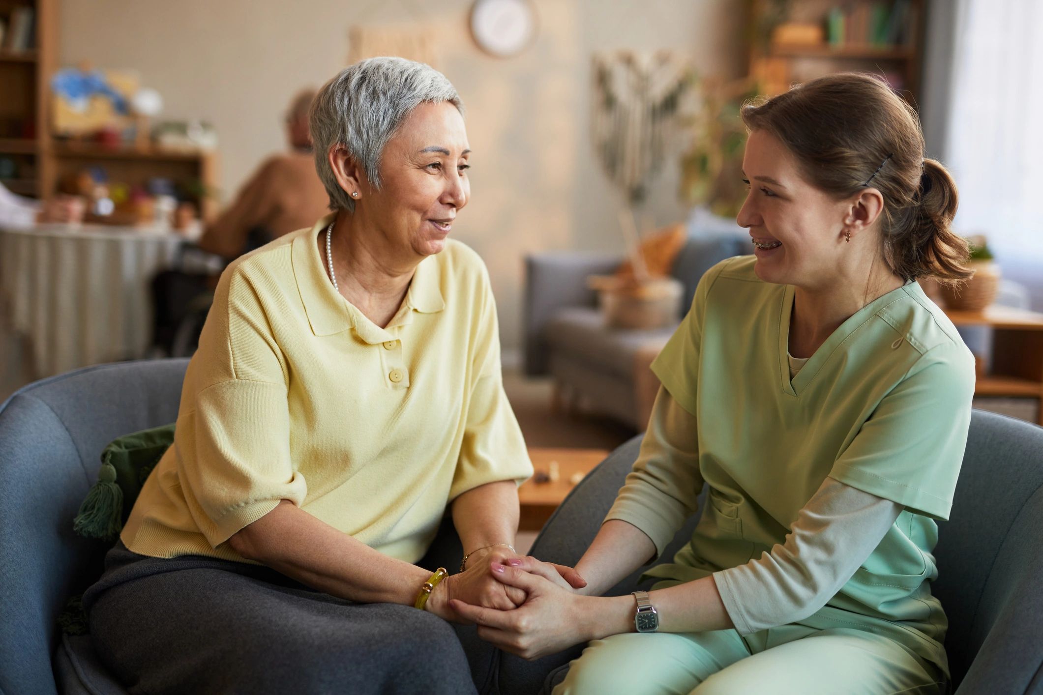 Senior woman holding hands with a caregiver during a compassionate visit