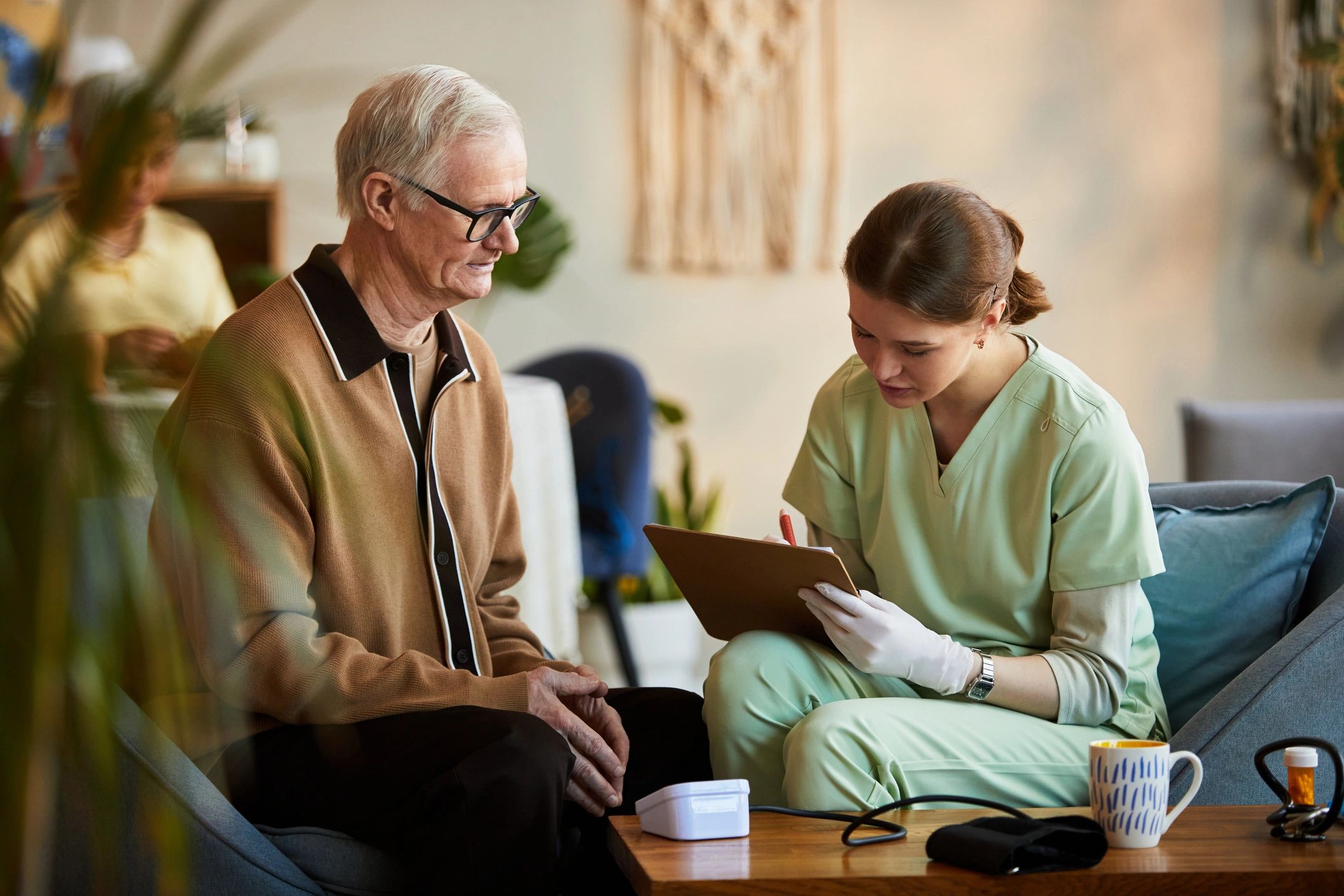 Nurse reviewing care notes with a senior man during a home health visit